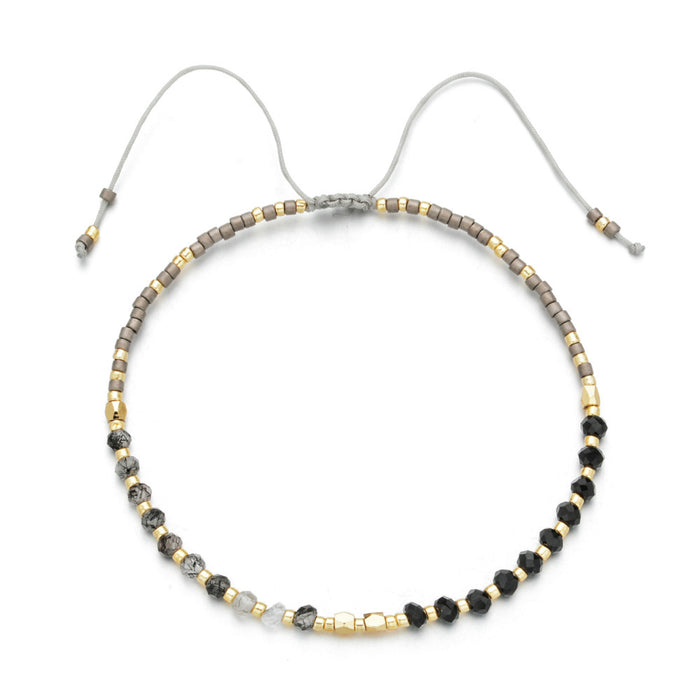 A delicate beaded bracelet featuring gray, black, and gold beads with an adjustable cord closure, crafted as part of the Japanese Handmade Bead Bracelets | Live Love Spa collection.