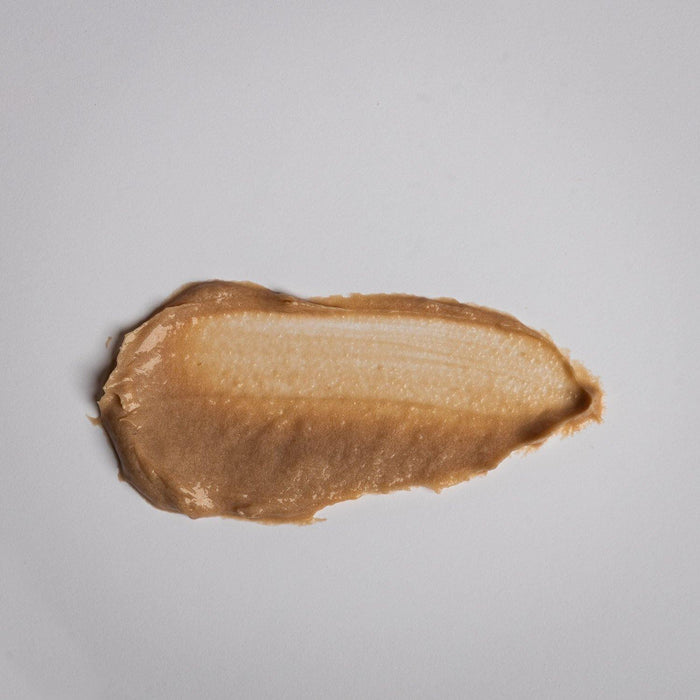 A smooth swatch of Kantic® Brightening Moisture Mask | Alchimie Forever skincare product with a creamy, light brown texture on a white surface.