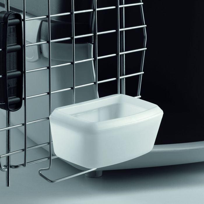 White background with a close up of the white water bowl clipped on the inside of a Krusse Stefanplast Travel Cage.