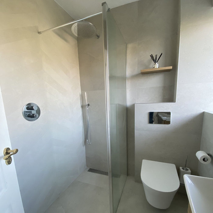 Bathroom with greige stone effect tiles shower and wall hung WC.