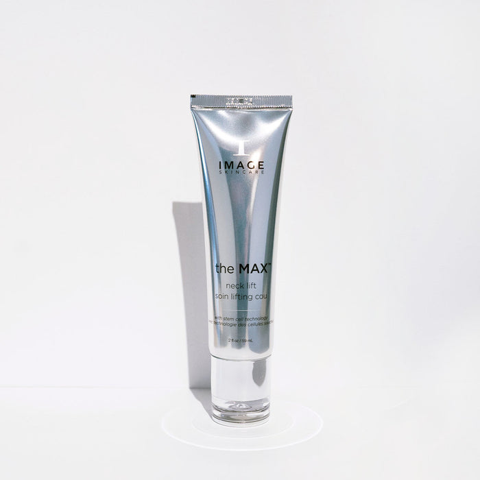 Silver tube of MAX™ neck lift | IMAGE Skincare standing upright on a white surface with minimalistic lighting highlighting the sleek packaging for skincare and body care wellness.