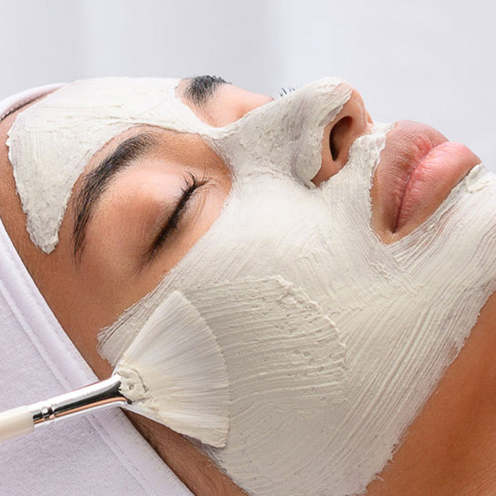 Close-up of a person with eyes closed receiving a smooth application of Miracle Mask | HydroPeptide skincare product on their face with a soft brush, promoting facial wellness.