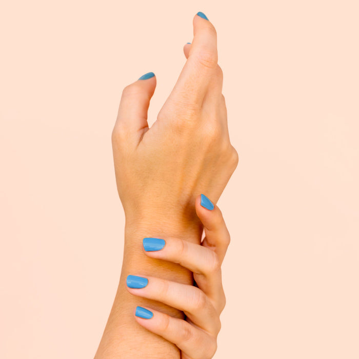 Blue Lagoon BKIND nail polish on hands – bright blue vegan manicure in Calgary
