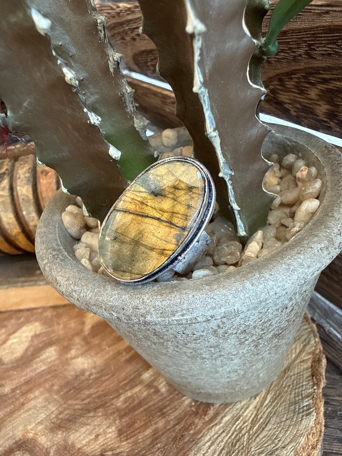Adjustable ring with oval yellow stone in silver-toned bezel setting