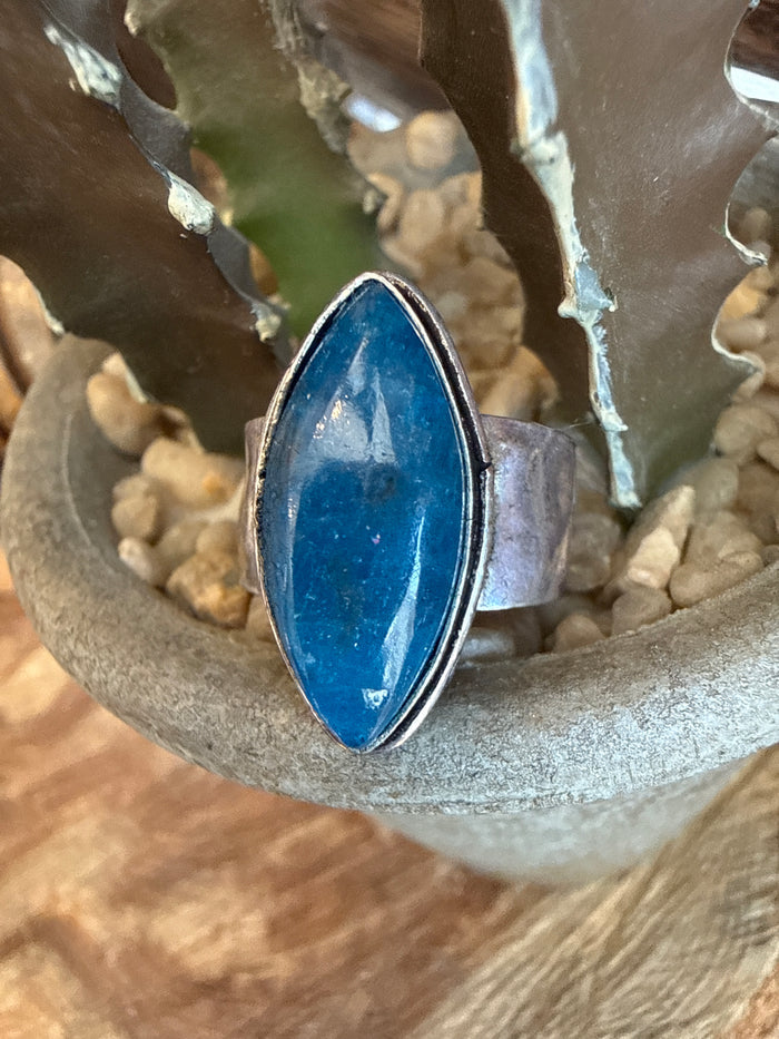Adjustable ring with oval blue stone in silver-toned bezel setting