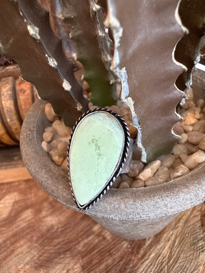 Adjustable ring with oval pale green stone in silver-toned bezel setting