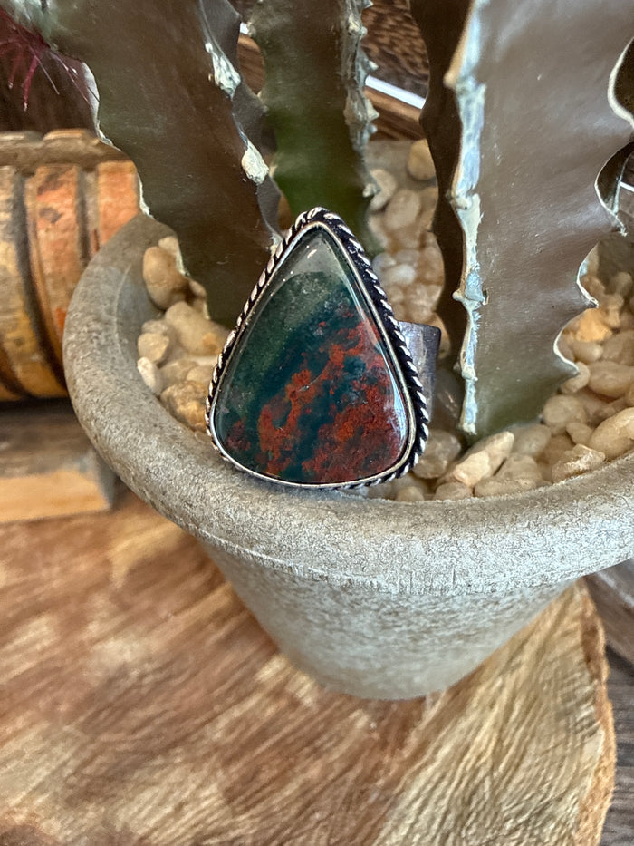 Adjustable ring with oval red stone with dark matrix in silver-toned bezel