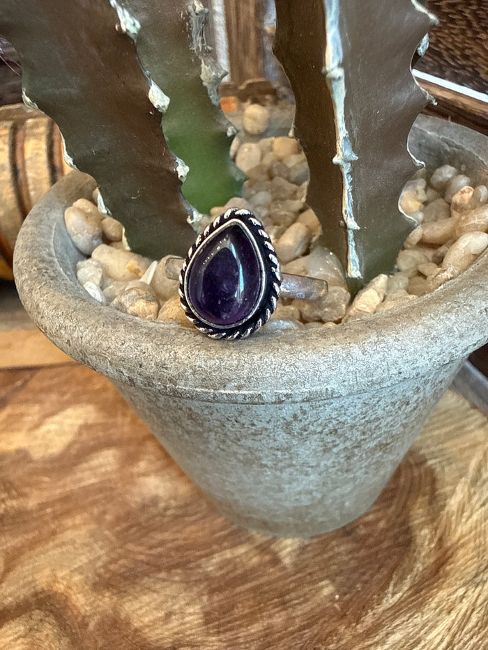 Adjustable brass ring with oval purple stone bezel and dark beaded surround