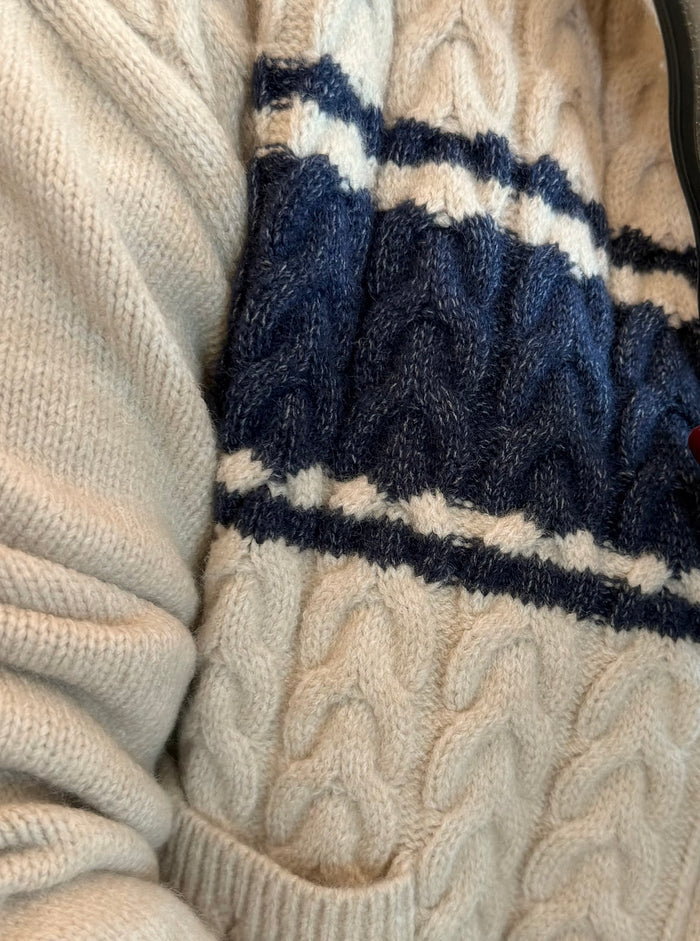 Cable-knit varsity cardigan with navy-and-taupe stripe bands and zip front, close-up