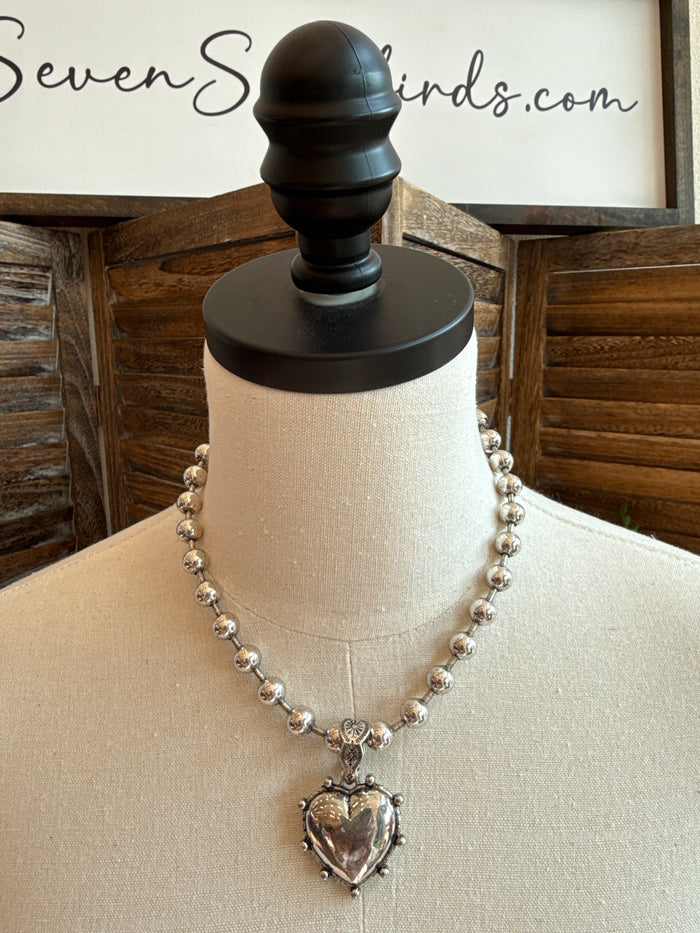 Silver-tone bead necklace with puffed heart pendant and small dangling charm details