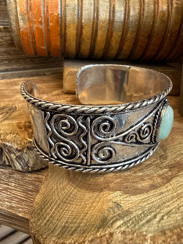 Silver-tone cuff bracelet with ornate filigree design and oval turquoise cabochon