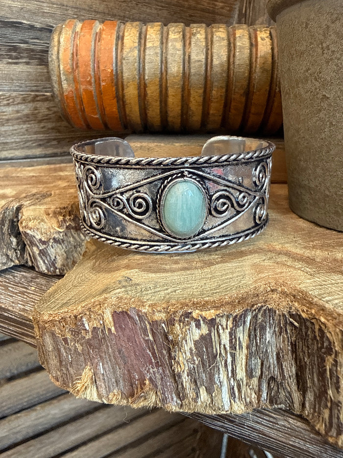 Silver-tone cuff bracelet with braided edge and oval turquoise cabochon center stone