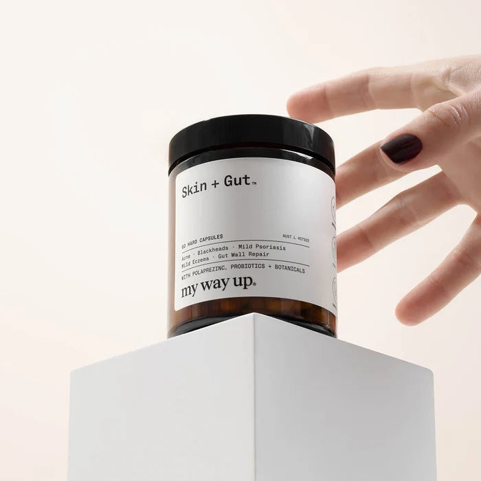 Hand holding a jar labeled 'Skin + Gut' with a white background