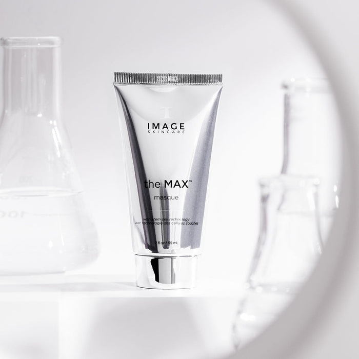 Silver tube of the MAX™ masque | IMAGE Skincare displayed in a clean, bright setting with laboratory glassware in the background, highlighting skincare and wellness.