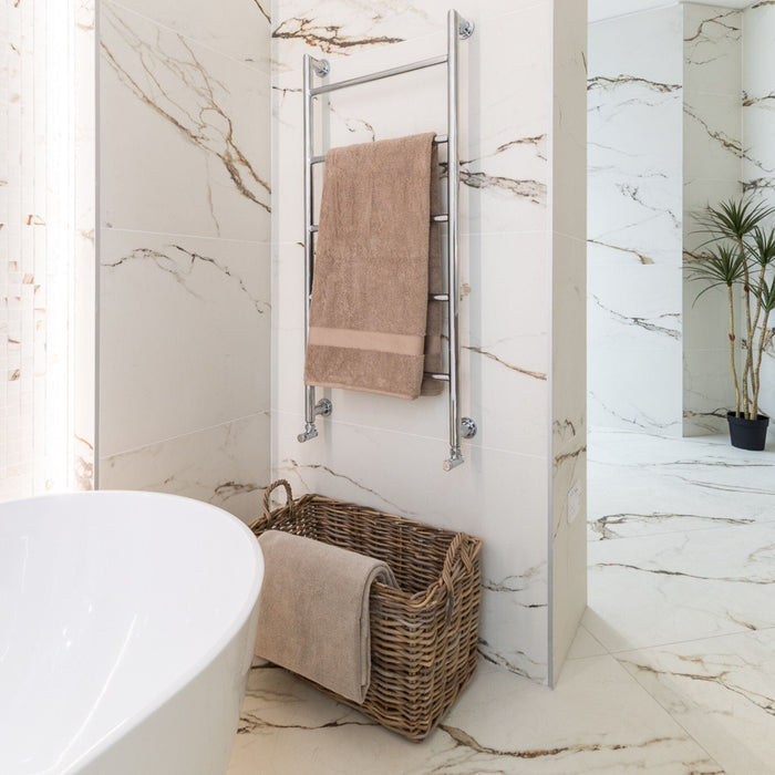 Bathroom with marble effect tiled walls, a towel rack with a brown towel, and a woven basket.