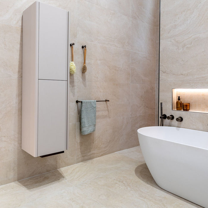 Modern bathroom with a freestanding bathtub, wall-mounted cabinet and beige stone effect tiles.