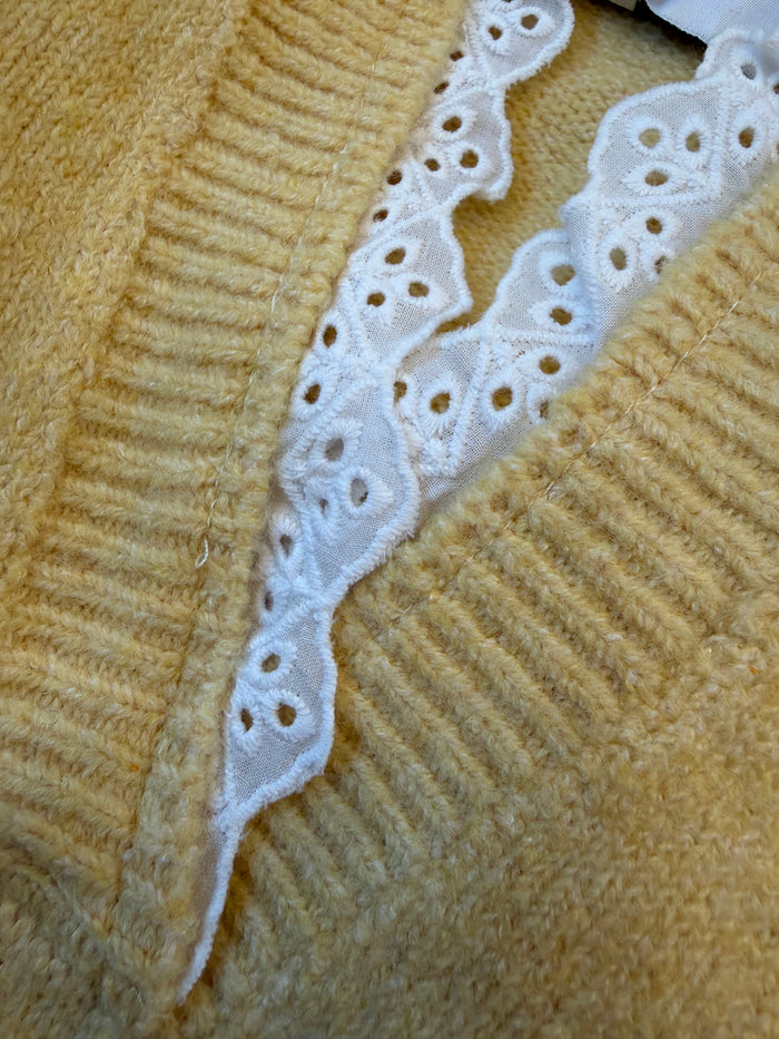 Yellow knit sweater front with white scalloped lace trim V-neck detail