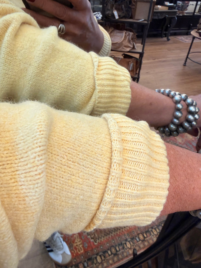 Yellow knit sweater with white lace-trimmed V neckline and ribbed cuffs